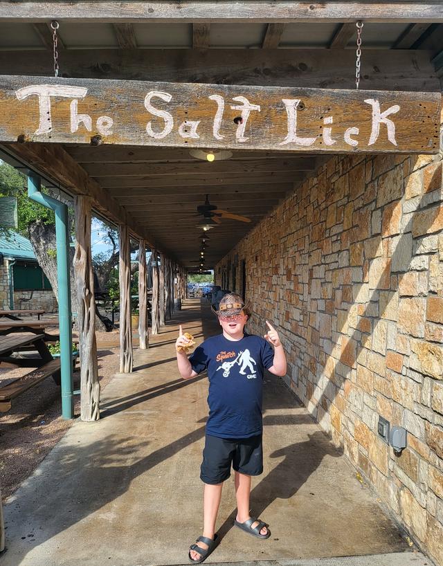 Conor giving a thumbs up beneath a hand-painted sign reading The Salt Lick